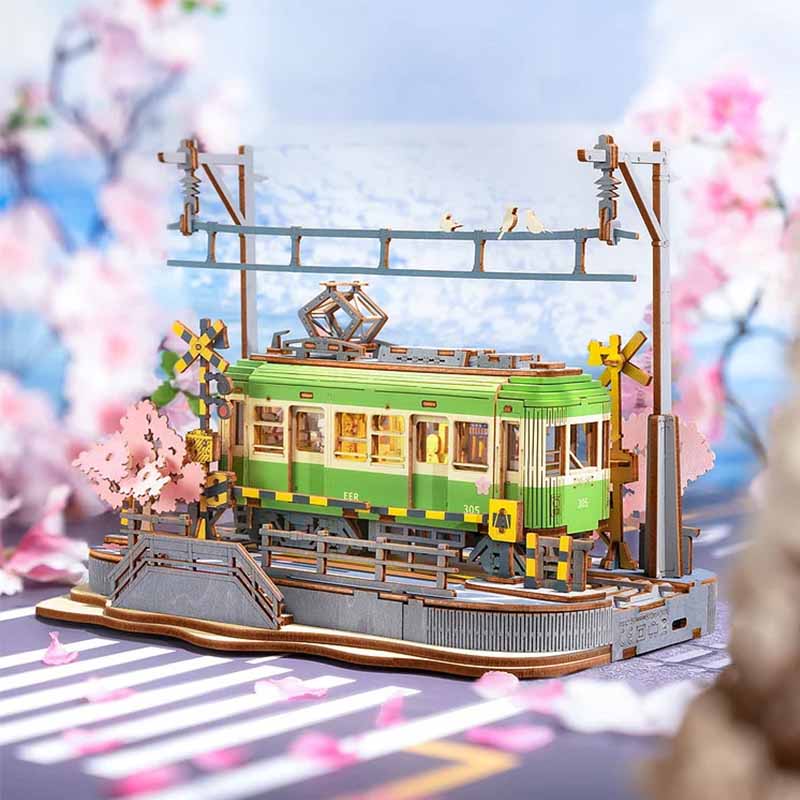 Tranvía Sakura Journey de Robotime Rolife, puzzle 3D de madera con diseño detallado de un tranvía japonés iluminado por luces LED, rodeado de cerezos en flor, ideal para mayores de 14 años. Primer plano con fondo.